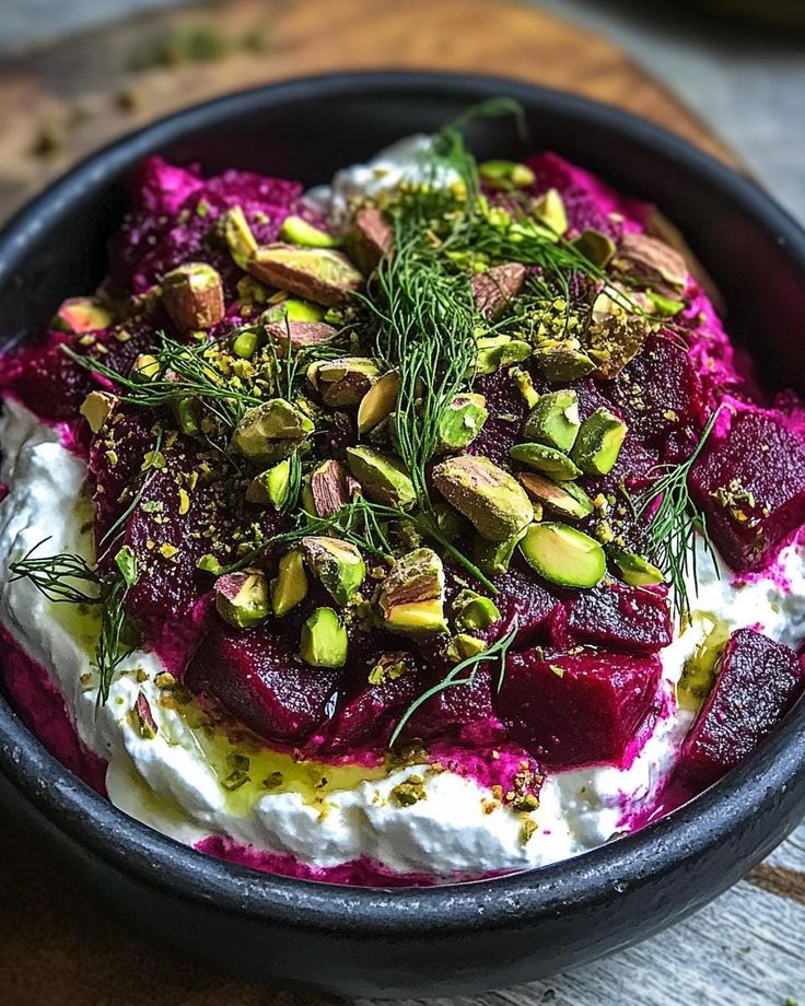 A bowl of labneh topped with roasted beets, pistachios, and dill.